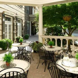A charming outdoor patio with tables and chairs, surrounded by greenery.