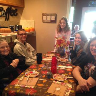 A group of people enjoying a casual gathering around a dining table decorated for autumn.