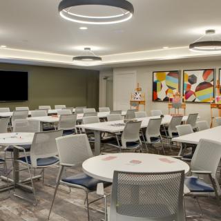 A modern conference room with circular tables, mesh chairs, and colorful artwork on the walls.