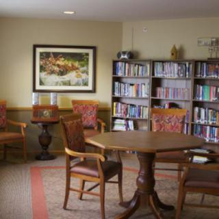A cozy library corner featuring bookshelves, a round table, and chairs for reading.