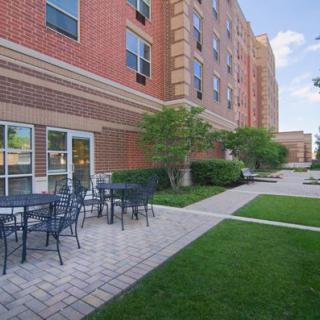 Outdoor patio area of an apartment building with tables and chairs surrounded by green lawns.