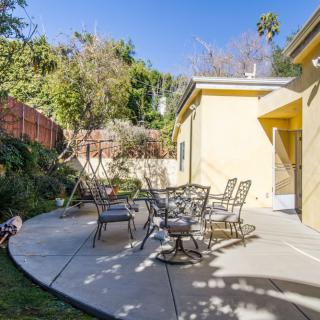 A sunny backyard patio with outdoor furniture and lush greenery.
