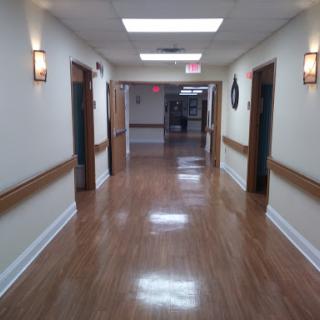 A spacious, well-lit hallway with wooden flooring and doors on either side.