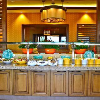 A vibrant buffet display in a restaurant, showcasing a variety of dishes under warm decorative lighting.
