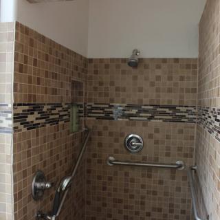 A tiled shower area with grab bars and a built-in shelf.