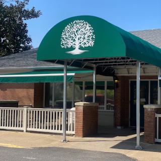 A building entrance with a green canopy featuring a tree logo.