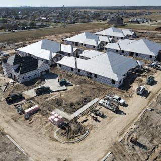 Aerial view of a residential construction site featuring multiple buildings with modern roofs under development.