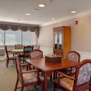 A dining room with tables, chairs, and a cabinet by the window.