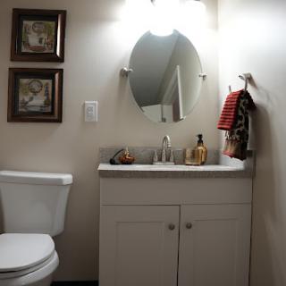 A compact bathroom featuring a vanity with a sink, a toilet, and decorative elements on the walls.