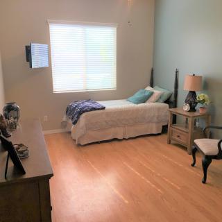 A minimalist bedroom with a single bed, a lamp, and a chair near the window.