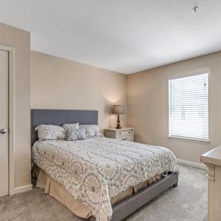 A cozy bedroom with a large bed, nightstands, and a lamp next to a window.