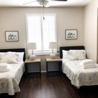 A tidy bedroom with twin beds, featuring matching lamps and artwork on the walls.