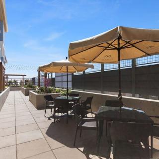 A sunny outdoor patio with tables, chairs, and umbrellas.