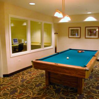 A cozy recreation room featuring a billiard table and a computer workstation.