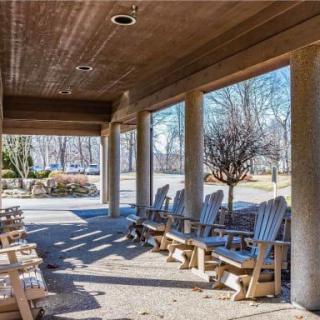A covered porch with multiple wooden rocking chairs, providing a shaded outdoor seating area.