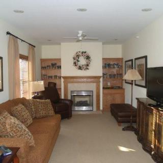 A cozy living room featuring a brown sofa, fireplace, and television.