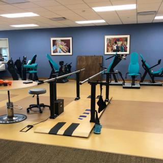 A physical therapy gym with various exercise machines and equipment.
