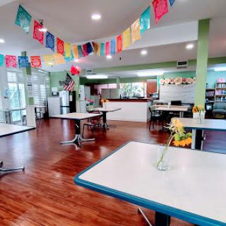 A vibrant cafeteria space featuring colorful banners and wooden flooring, inviting and ready for gatherings.