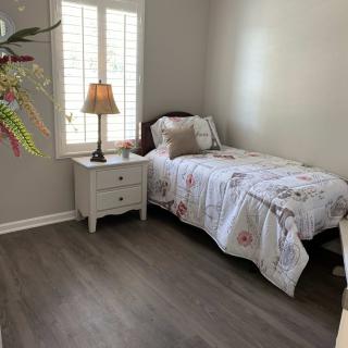 A cozy bedroom with a single bed, nightstand, and lamp by the window.