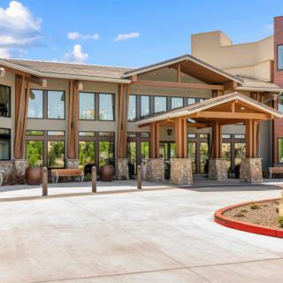 A modern building entrance with large windows and a covered entryway under a clear blue sky.