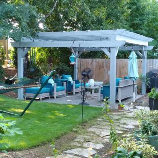 A cozy backyard gazebo with comfortable seating surrounded by lush greenery.