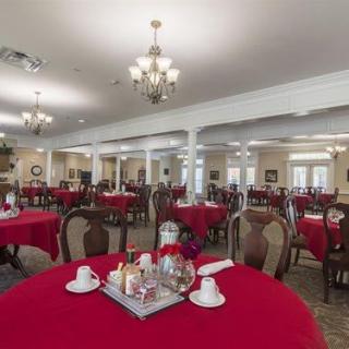 An elegant dining room featuring tables with red tablecloths and chandeliers.