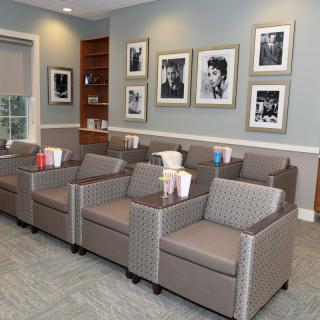 A neatly arranged waiting room with comfortable armchairs and framed photographs on the wall.