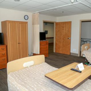 A hospital room with beds, wardrobes, and a television.