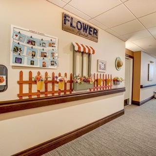 A hallway decorated with a flower theme, featuring a small fence and window display.