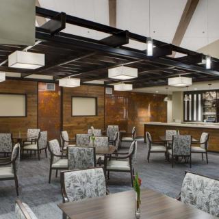 A modern restaurant interior with neatly arranged tables and chairs, featuring contemporary lighting.