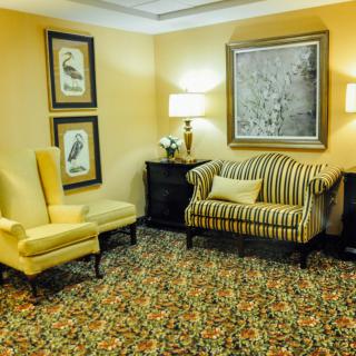 A cozy living room with a striped sofa and a yellow armchair, complemented by elegant artwork and warm lighting.
