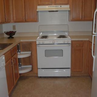 A clean kitchen with wooden cabinets and a white stove.