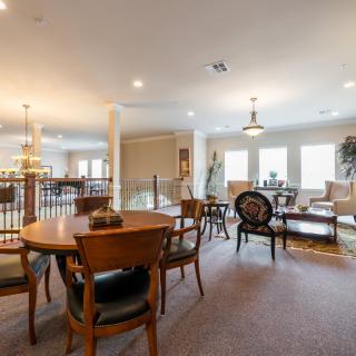 A spacious dining and living area with multiple tables, chairs, and ample lighting.