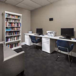 A modern office space with two computer workstations, a bookshelf, and a printer.
