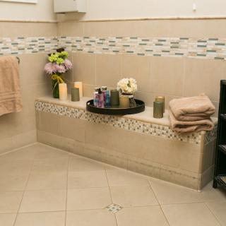 A cozy bathroom setup with candles, towels, and flowers for a relaxing ambiance.