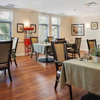 An inviting dining room with neatly arranged tables and chairs, decorated with plants and art on the walls.