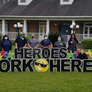 A dedicated team of healthcare workers stands proudly next to a sign celebrating their contributions.