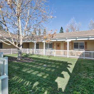A single-story building with a fenced yard, featuring a tree and well-maintained grass.
