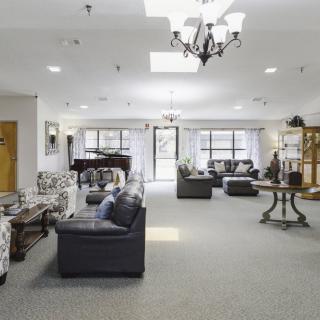 A spacious and elegantly decorated lounge area with comfortable seating, a grand piano, and ample natural light.