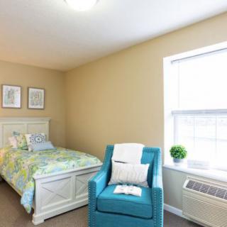 A cozy bedroom with a single bed and an armchair by the window.