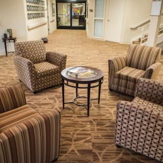 A cozy corner in a lobby featuring striped and patterned seating arrangements around a small table.