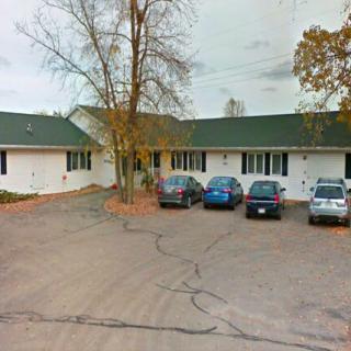 A small parking lot in front of a single-story building on an overcast day.