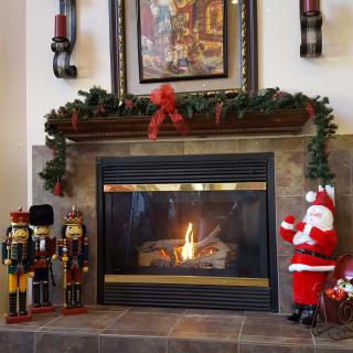 A cozy fireplace adorned with festive Christmas decorations, including a Santa Claus figure, nutcrackers, and garland.