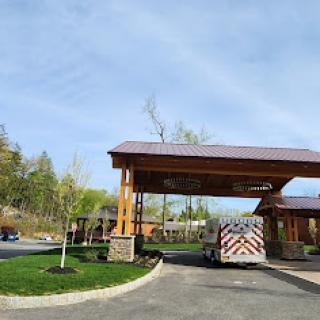 A welcoming entrance with a wooden canopy and a vehicle parked on a sunny day.