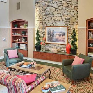 A cozy living room featuring a stone fireplace, comfortable chairs, and tasteful decor.