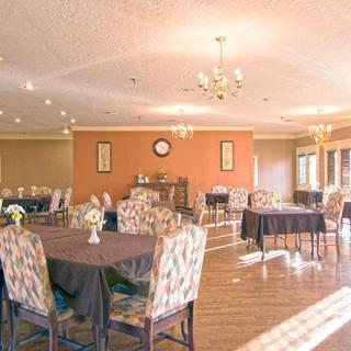 A spacious dining room with multiple tables, decorated with chandeliers and art on the walls.