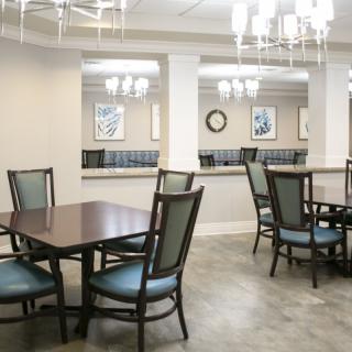 A modern dining area with multiple tables and chairs under elegant chandeliers.