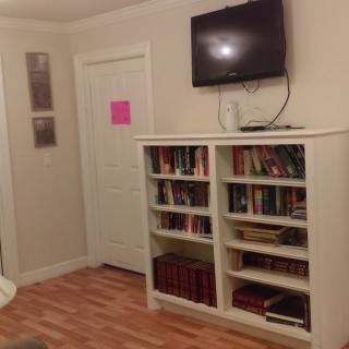 A cozy living room corner with a bookshelf filled with books and a TV mounted on the wall.