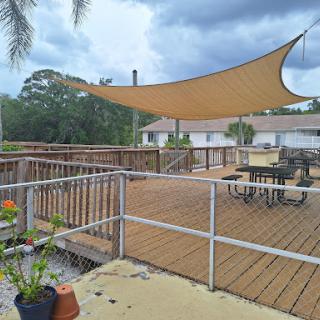 A spacious outdoor deck featuring a shade sail and comfortable furniture, perfect for relaxation.