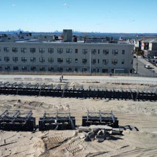 A view of a construction site with a large building in the background and machinery in the foreground.